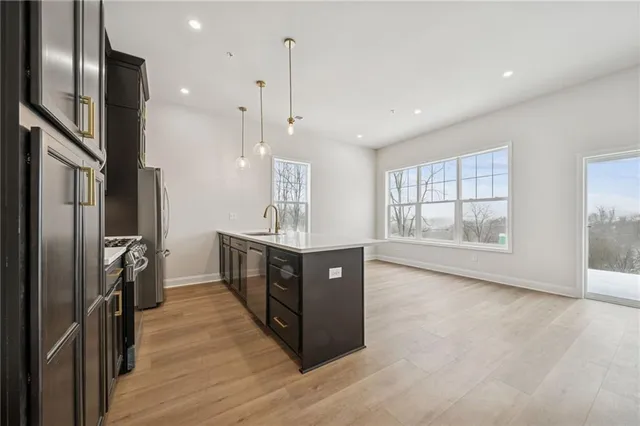 a kitchen with stainless steel appliances granite countertop a refrigerator a sink dishwasher a stove and a wooden floors