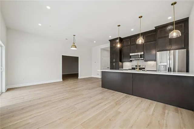 a kitchen with stainless steel appliances kitchen island granite countertop a refrigerator a sink and a microwave