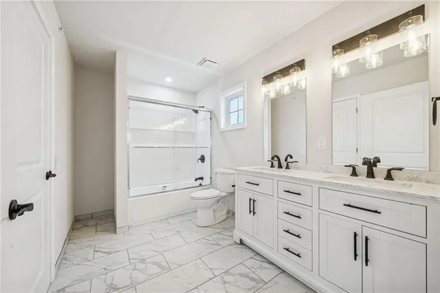 a bathroom with a granite countertop sink a toilet and a mirror