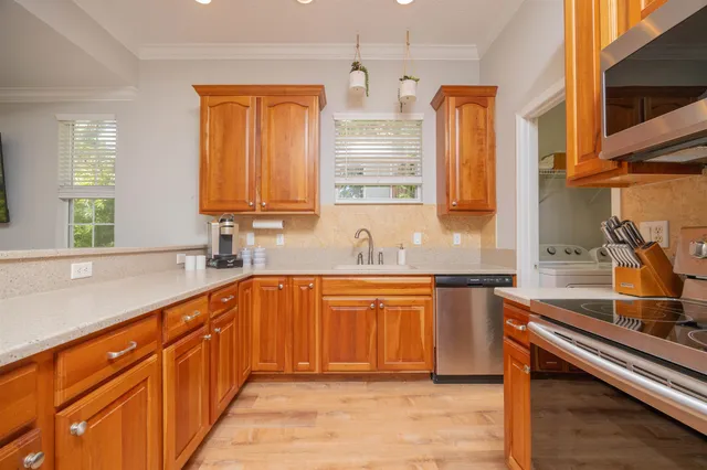 a kitchen with stainless steel appliances granite countertop a sink dishwasher stove and cabinets with wooden floor