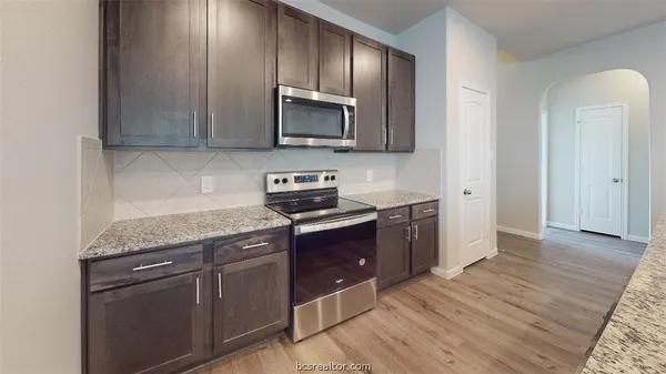 a kitchen with stainless steel appliances granite countertop a stove a sink and a microwave