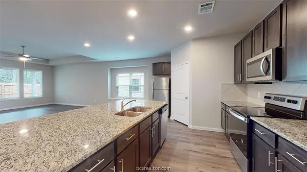 a kitchen with stainless steel appliances granite countertop a sink stove and refrigerator
