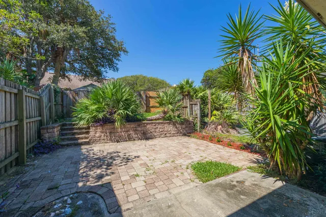 a view of a house with a small yard plants and wooden fence