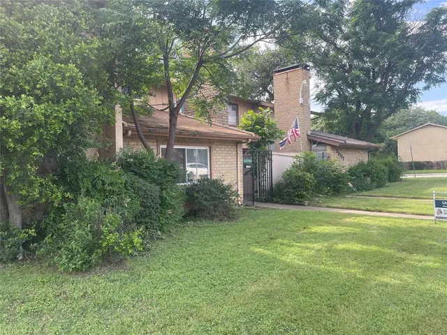 a view of a house with a yard and a large tree