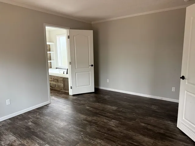 a view of an empty room with wooden floor and closet