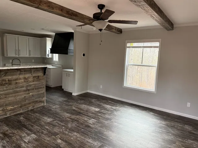 a view of a kitchen with wooden floor a ceiling fan and windows
