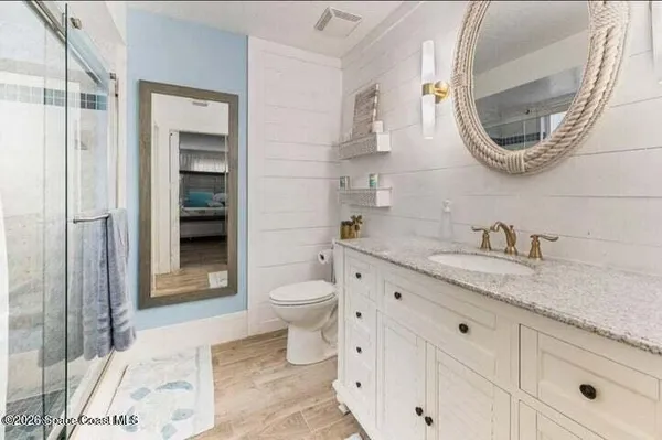 a bathroom with a granite countertop toilet sink and mirror
