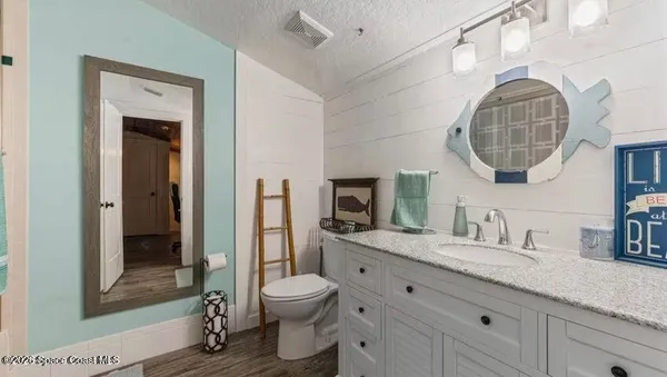 a bathroom with a granite countertop sink mirror vanity and toilet