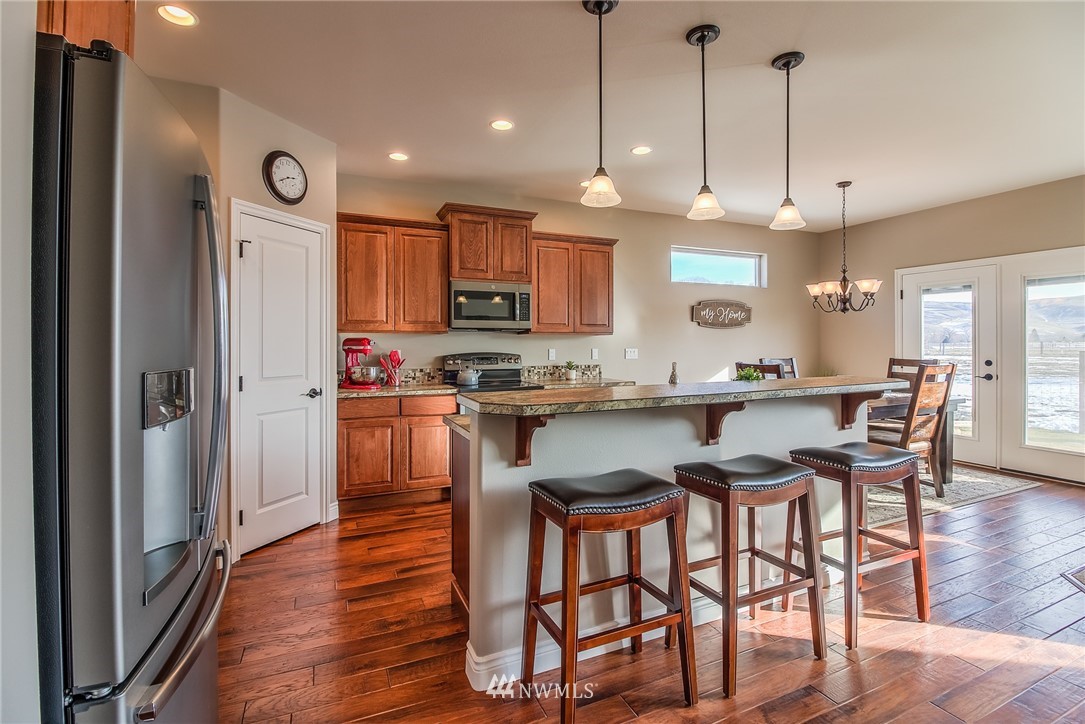 5904 Crestfields Road Yakima, WA 98903 - Photo 13 of 39 a kitchen with stainless steel appliances granite countertop a refrigerator a oven a sink a island and chairs with wooden floor