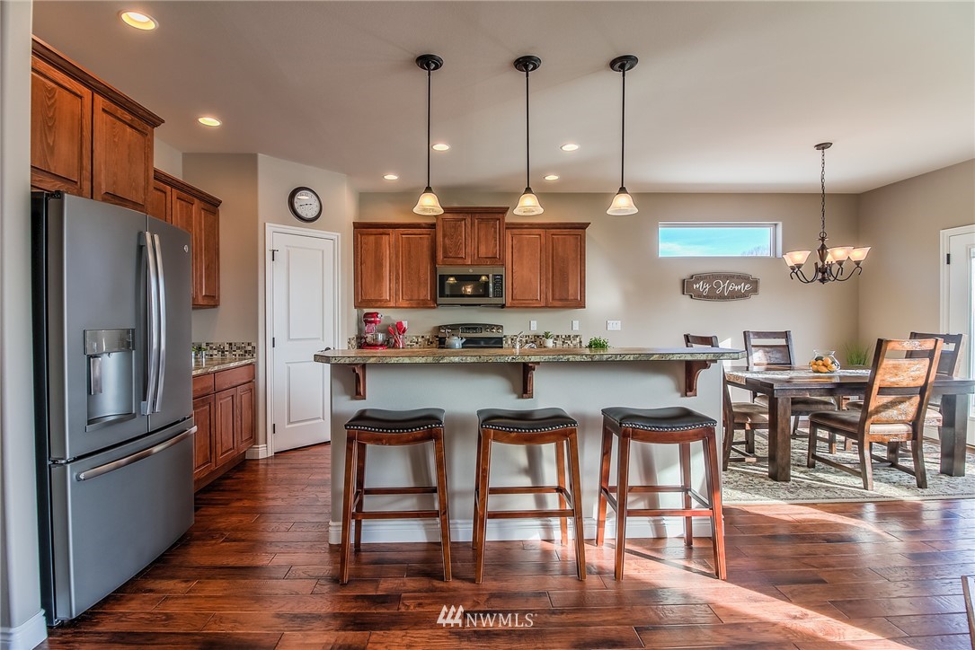 5904 Crestfields Road Yakima, WA 98903 - Photo 14 of 39 a kitchen with stainless steel appliances granite countertop a stove top oven a refrigerator a sink and a dining table with wooden floor