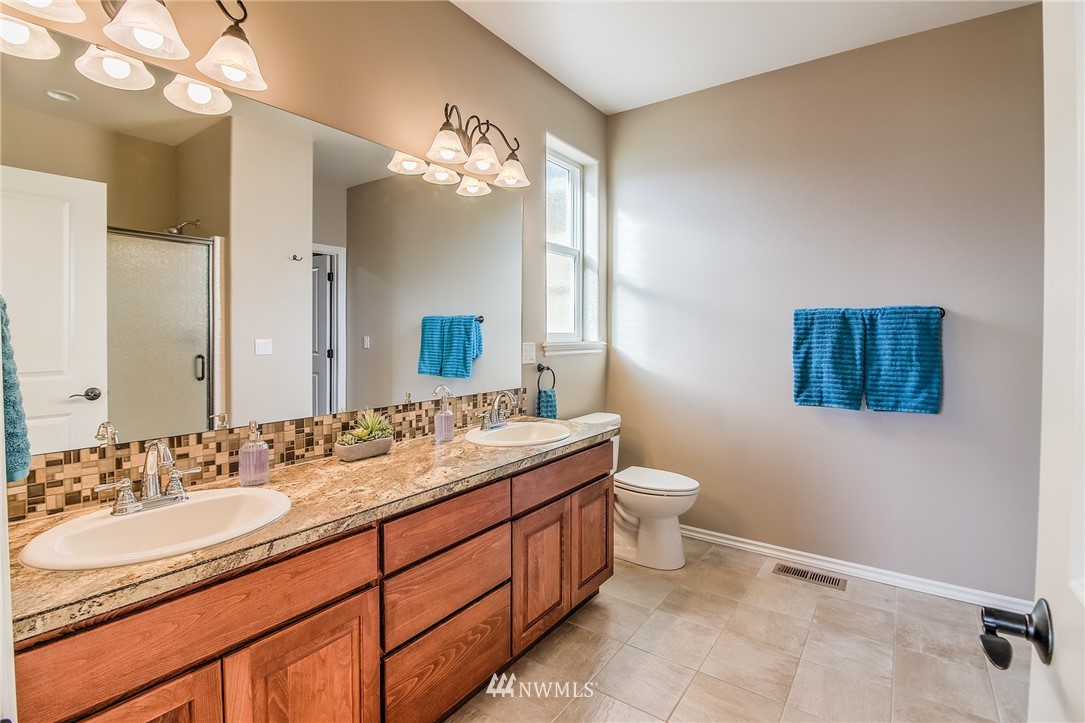 5904 Crestfields Road Yakima, WA 98903 - Photo 23 of 39 a bathroom with a granite countertop double vanity sink a mirror and a toilet
