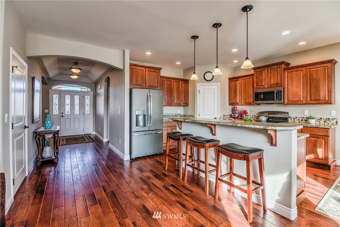 5904 Crestfields Road Yakima, WA 98903 - Photo 8 of 39 a kitchen with stainless steel appliances granite countertop a refrigerator a stove a sink dishwasher and a dining table with wooden floor