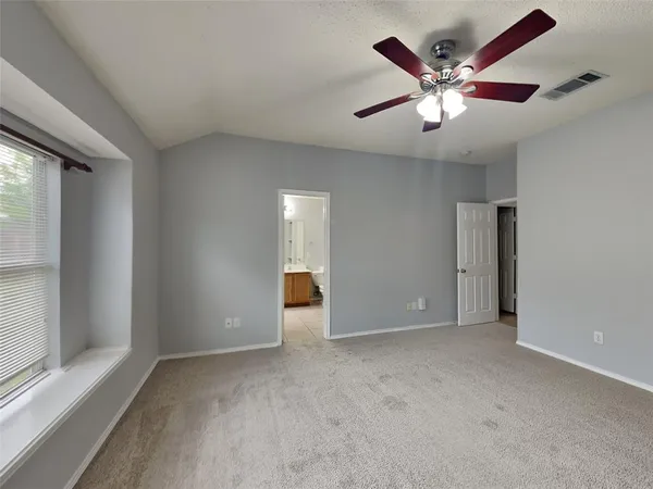 an empty room with chandelier fan and windows