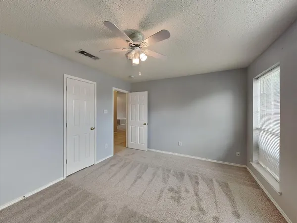 a view of an empty room with closet and a window