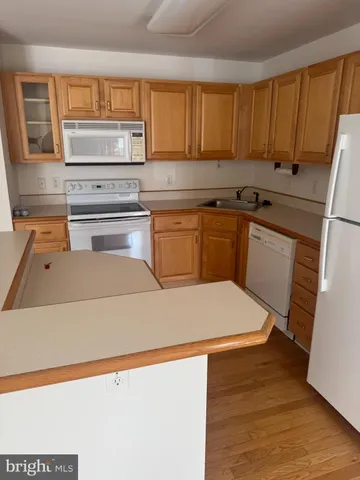 a kitchen with kitchen island a stove a sink and a refrigerator with wooden floor