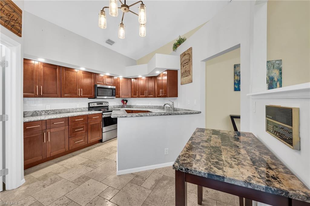 181 Napa Ridge Road East, Unit 35 Naples, FL 34119 - Photo 7 of 21 Kitchen featuring dark wood cabinetry, light-colored granite countertops, and a subway tile backsplash