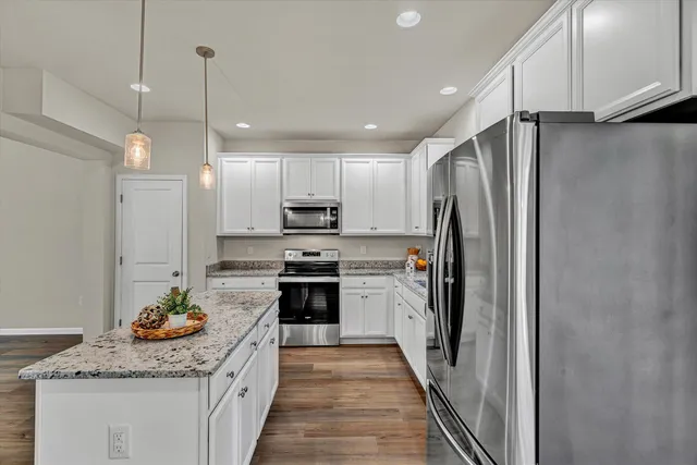 a kitchen with stainless steel appliances granite countertop a refrigerator a stove and a sink