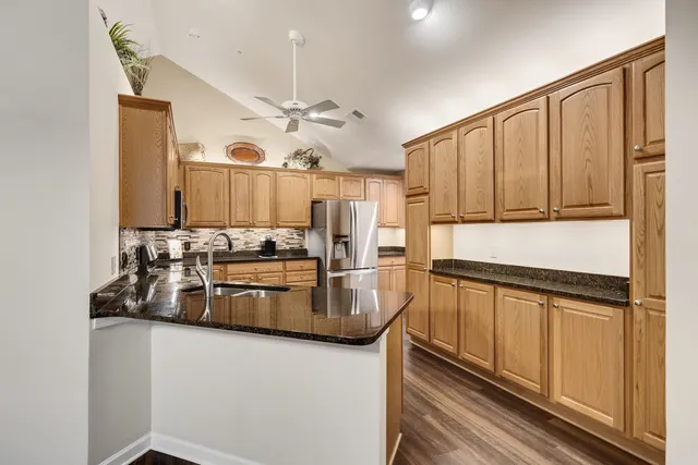 a kitchen with stainless steel appliances granite countertop a refrigerator a stove and a sink with large cabinets
