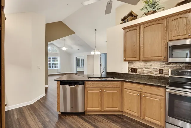 a kitchen with stainless steel appliances granite countertop a sink and cabinets with wooden floor