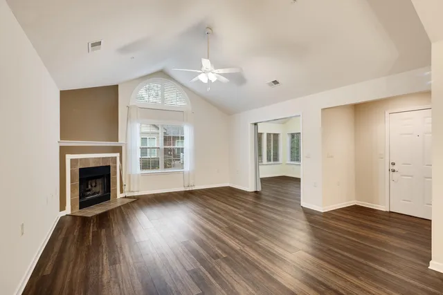 a view of an empty room with wooden floor fireplace and a window