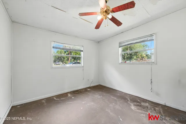 an empty room with window and ceiling fan