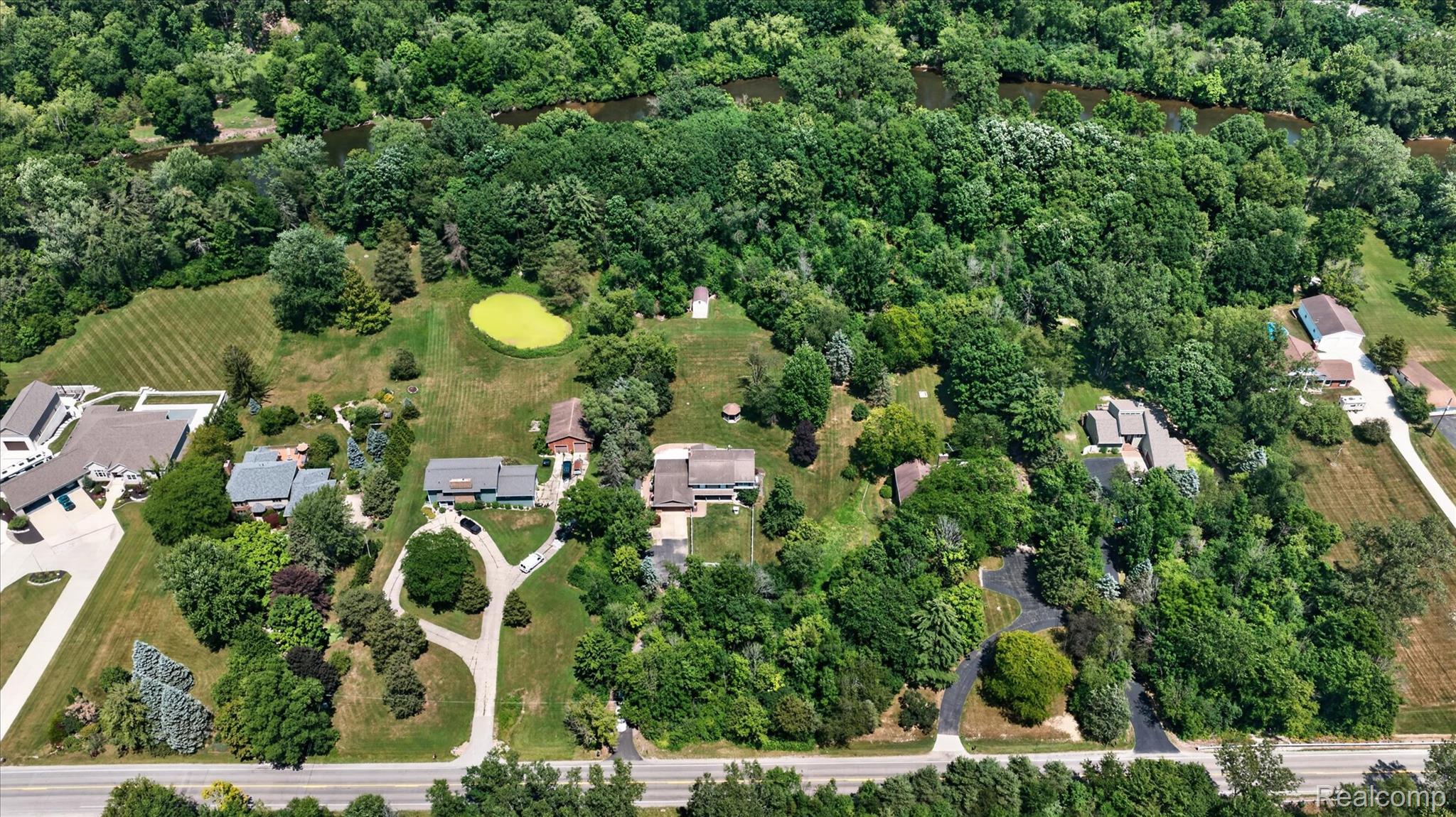 7186 East River Road Flushing, MI 48433 - Photo 30 of 47 Aerial rendering of a wooded property featuring a river and a pond