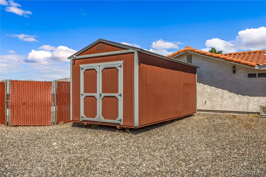 4088 Mercer Road Bullhead City, AZ 86429 - Photo 22 of 35 Freestanding storage shed with a gable roof and double doors, set on a gravel surface