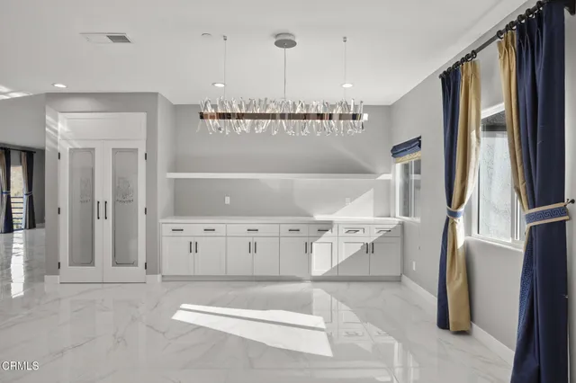 a large white kitchen with a sink dishwasher a stove and a dining table with wooden floor