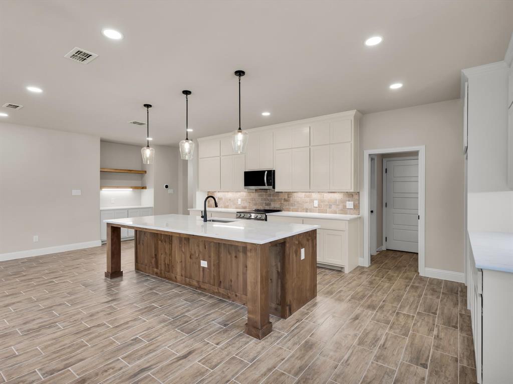 612 Jameson Springtown, TX 76082 - Photo 2 of 13 a large white kitchen with a sink and dishwasher stove with wooden floor