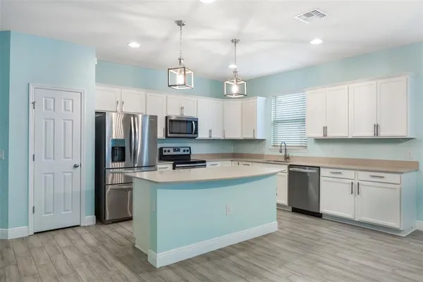 a kitchen with kitchen island granite countertop a sink cabinets and wooden floor