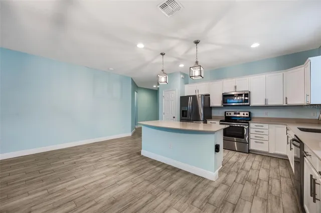 a large kitchen with granite countertop a stove top oven a sink dishwasher a dining table and chairs with wooden floor