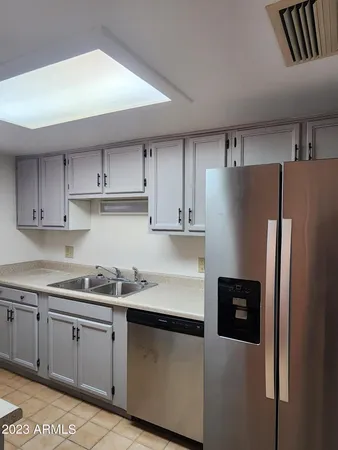 a kitchen with stainless steel appliances granite countertop a refrigerator a sink and white cabinets