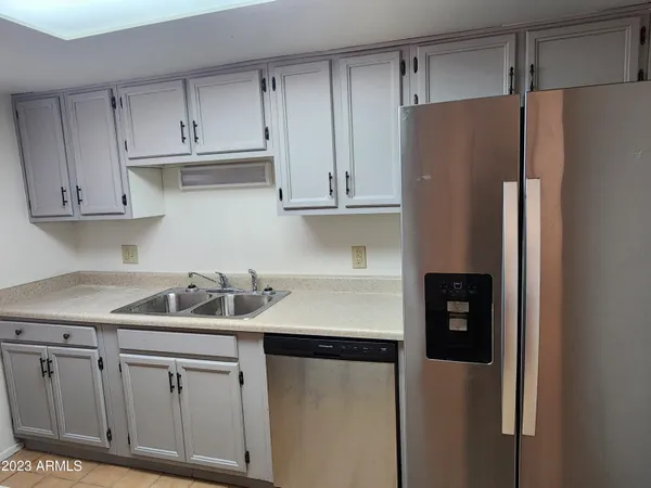 a kitchen with stainless steel appliances granite countertop a refrigerator a sink and white cabinets
