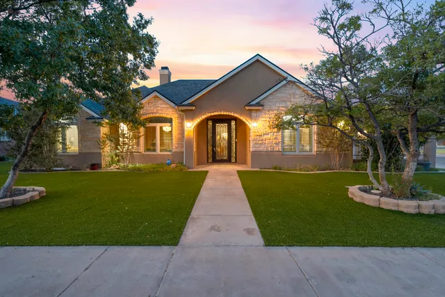 a front view of a house with a yard and trees