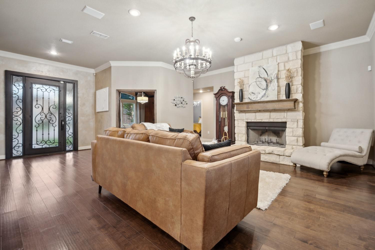 3902 101st Street Lubbock, TX 79423 - Photo 25 of 37 a living room with furniture a fireplace and a chandelier