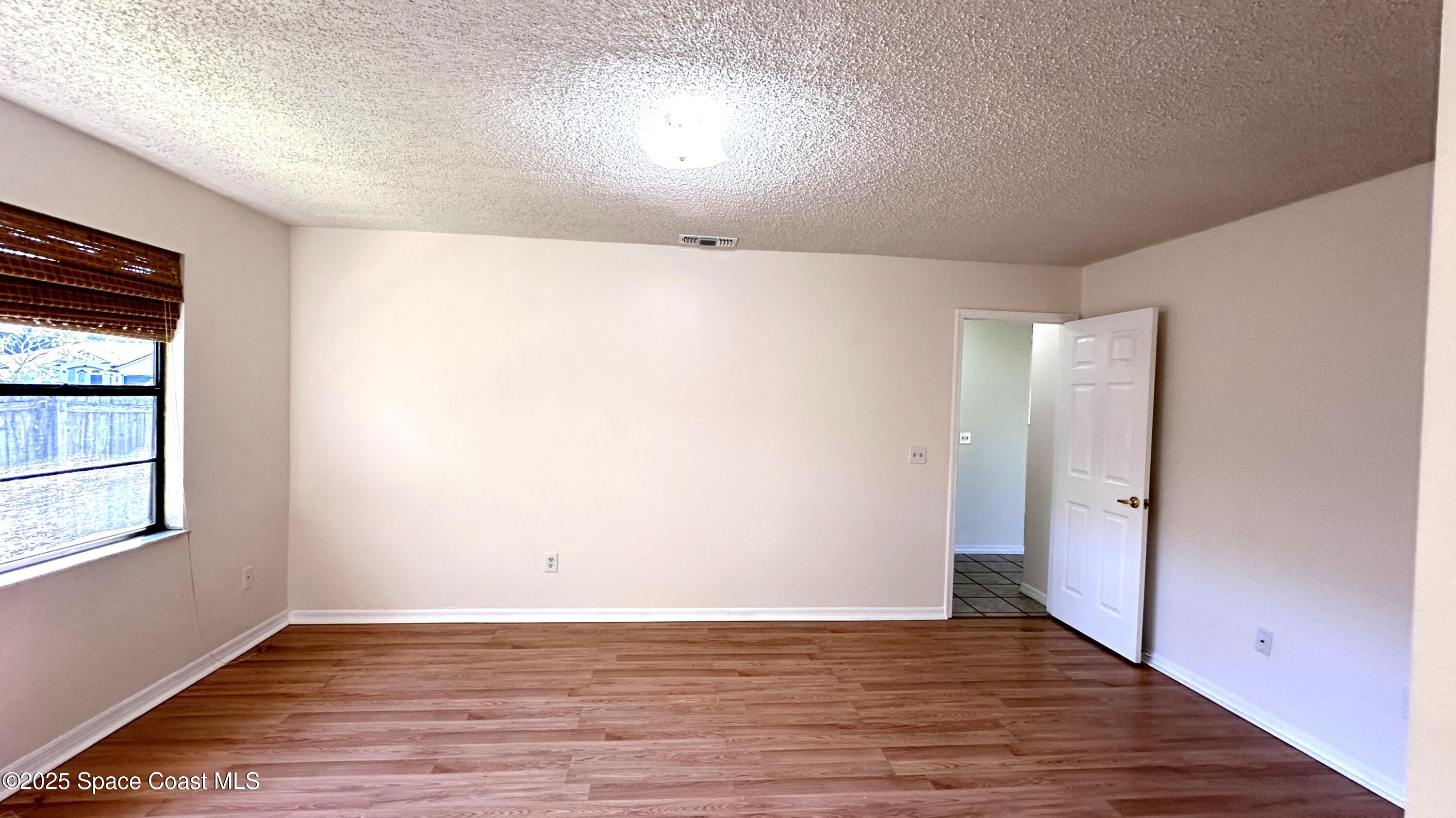 3807 Jupiter Boulevard Southeast Palm Bay, FL 32909 - Photo 23 of 34 an empty room with wooden floor and windows