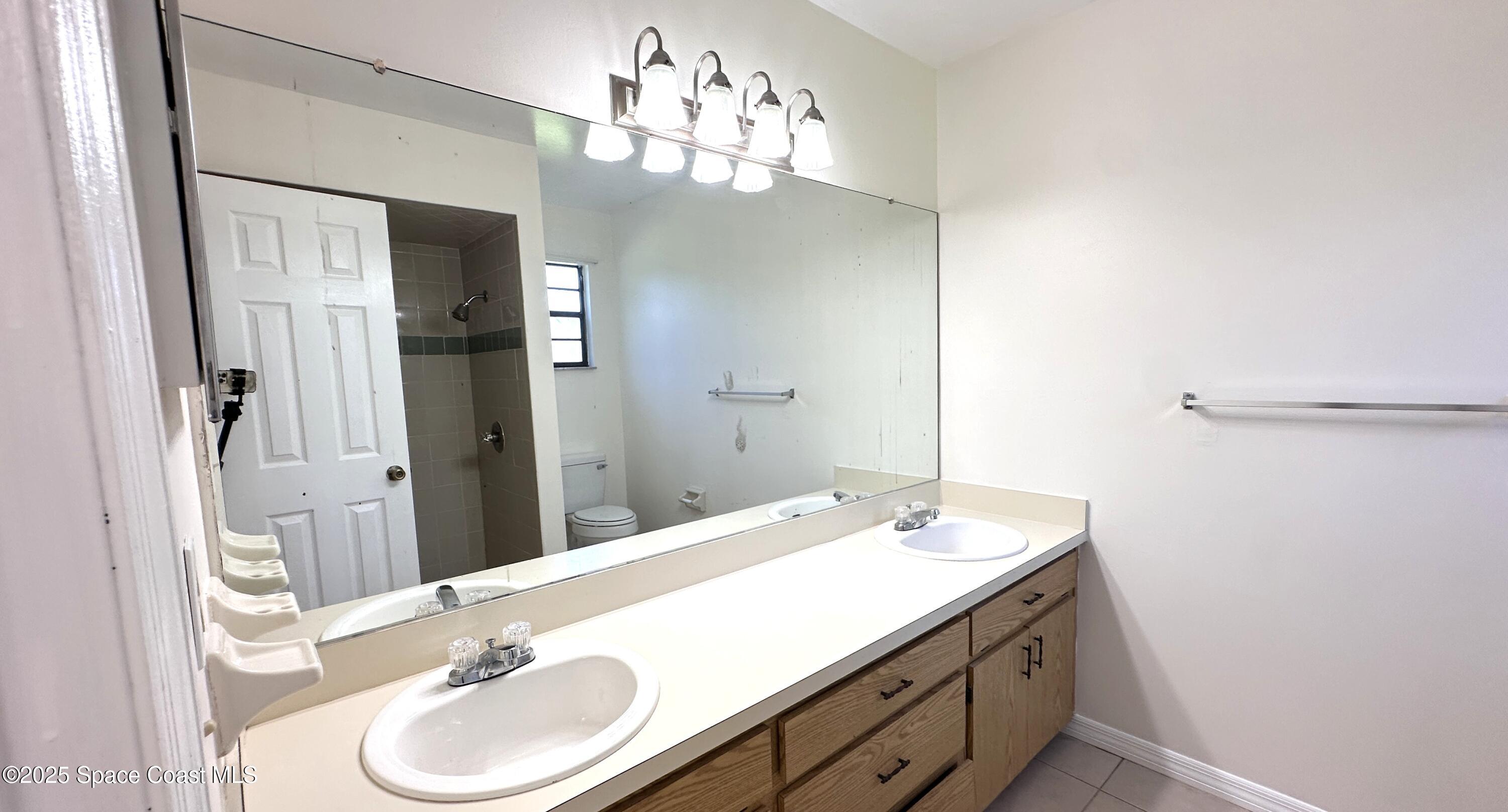 3807 Jupiter Boulevard Southeast Palm Bay, FL 32909 - Photo 27 of 34 a bathroom with a double vanity sink and a mirror