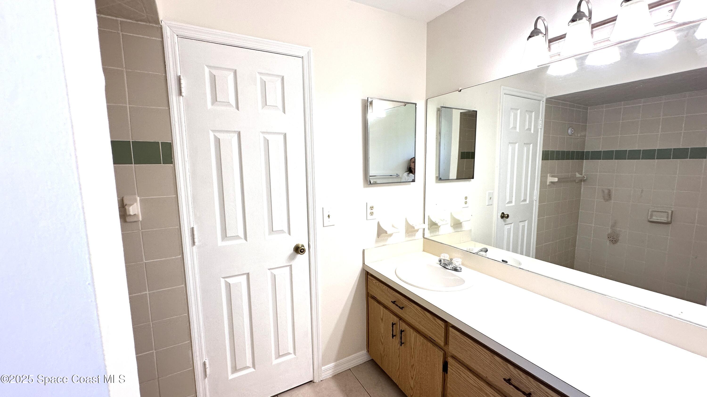 3807 Jupiter Boulevard Southeast Palm Bay, FL 32909 - Photo 30 of 34 a bathroom with a double vanity sink a mirror and a shower