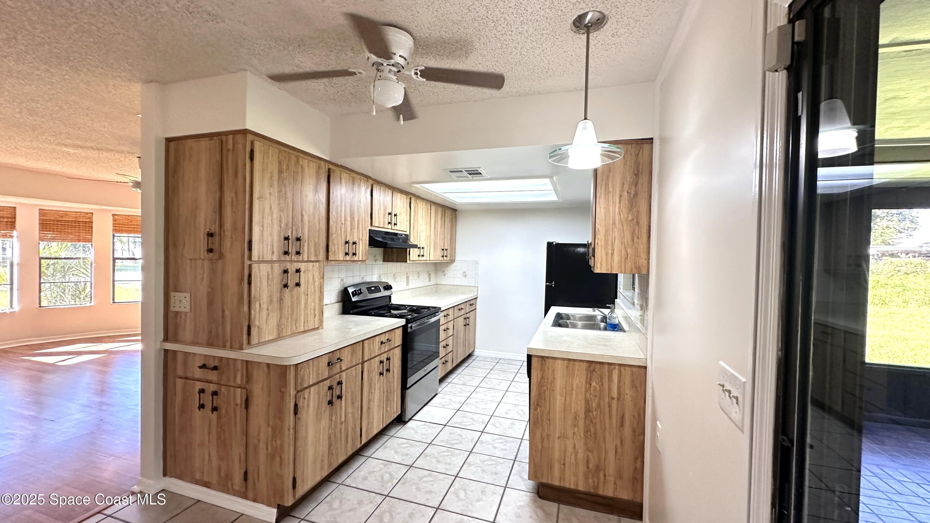 3807 Jupiter Boulevard Southeast Palm Bay, FL 32909 - Photo 6 of 34 a kitchen with stainless steel appliances a stove top oven a refrigerator a sink and dishwasher