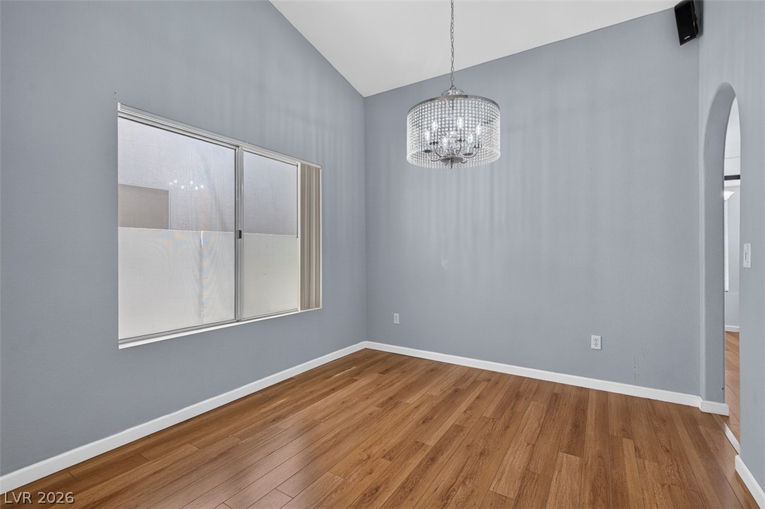 2609 Shakespeare Road Las Vegas, NV 89108 - Photo 10 of 41 Natural light illuminates rich hardwood flooring in the dining room, featuring a unique vaulted ceiling and elegant chandelier.