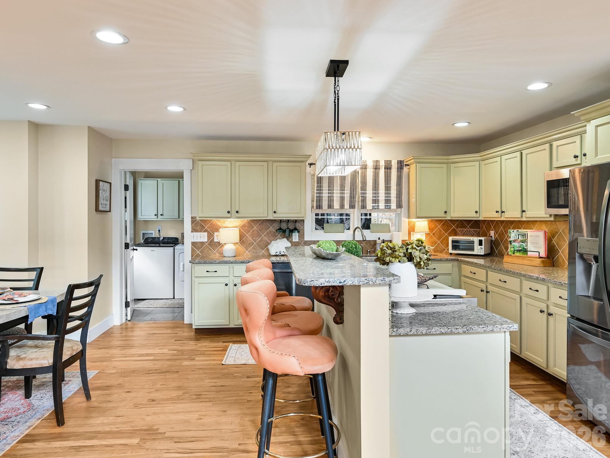 1645 Ivy Hill Road Marshall, NC 28753 - Photo 13 of 36 a kitchen with stainless steel appliances kitchen island granite countertop a refrigerator a stove top oven a sink dishwasher and white cabinets with wooden floor