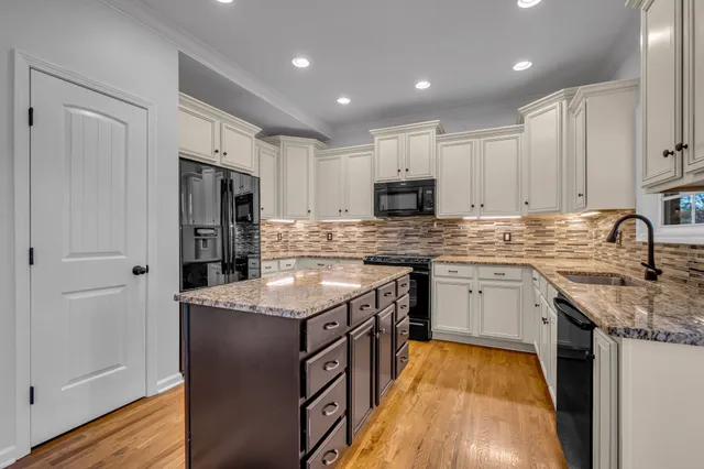 a kitchen with stainless steel appliances granite countertop a sink stove refrigerator and cabinets