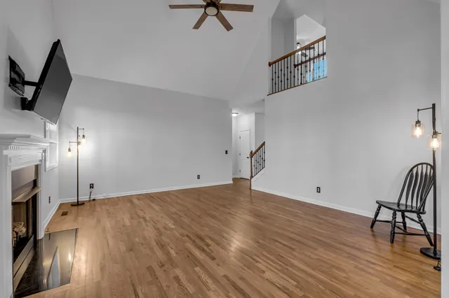 a view of empty room with wooden floor and fan