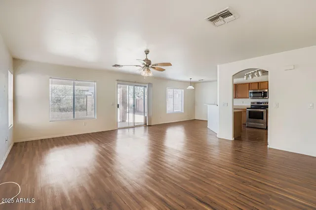 a view of an empty room with window and wooden floor