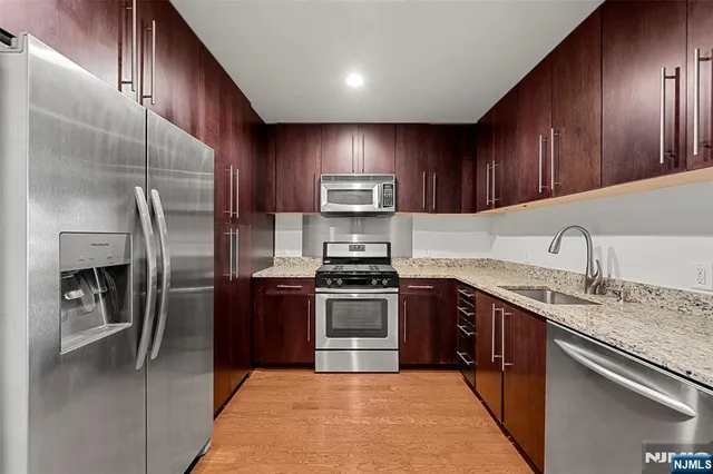 a kitchen with stainless steel appliances granite countertop a sink stove and refrigerator