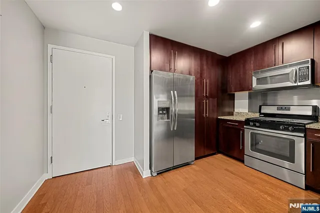 a kitchen with stainless steel appliances granite countertop a refrigerator and a stove top oven