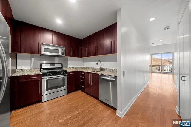 a kitchen with stainless steel appliances granite countertop wooden cabinets a stove a sink and a refrigerator