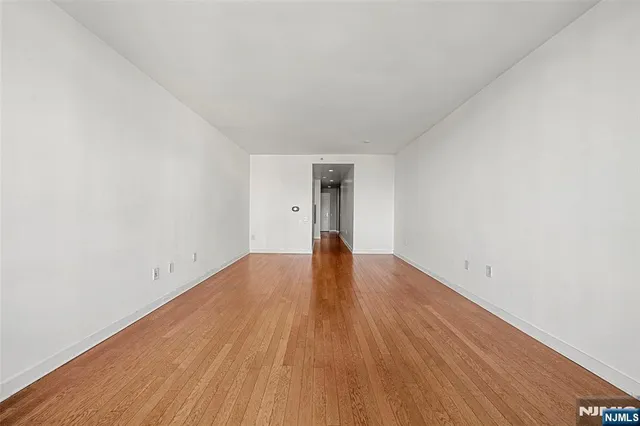 a view of empty room with wooden floor and natural light