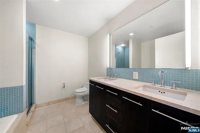 a bathroom with a double vanity sink toilet and a mirror