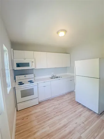 a kitchen with granite countertop white cabinets and white appliances